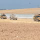 US troops, center, conduct a joint patrol with Turkish armored vehicles in Northeastern Syria.